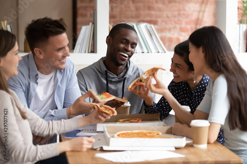 Diverse students eat pizza chatting take break distracted from study