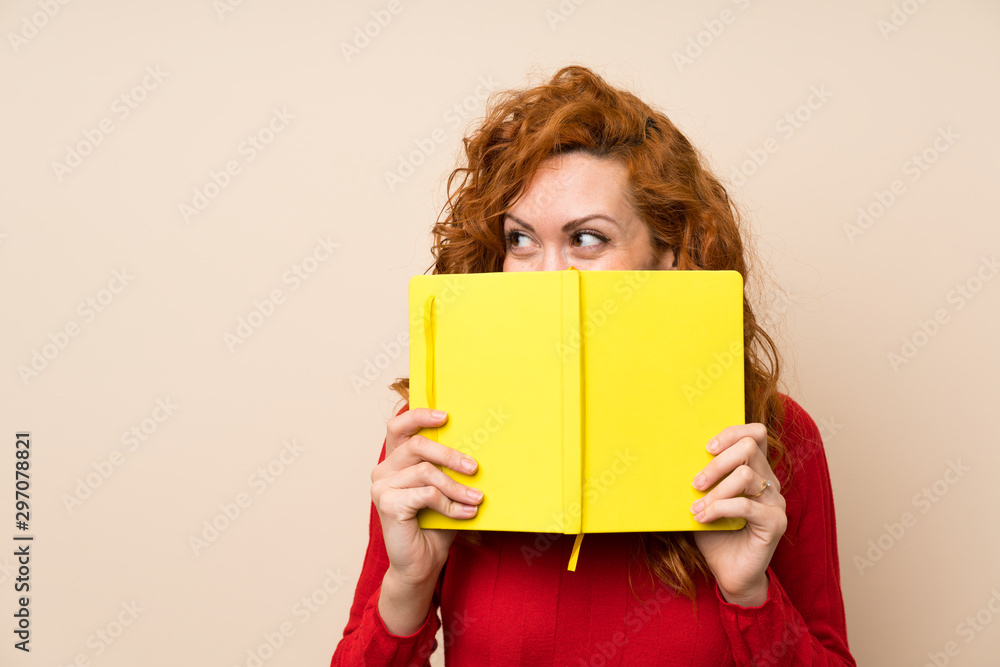 Redhead woman with turtleneck sweater holding and reading a book Redhead woman with turtleneck sweater holding and reading a book