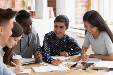 Focused multi national students sitting at desk studying together