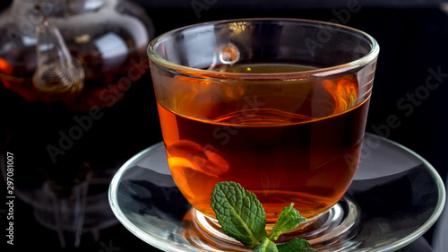 Cup of tea with a leaf of mint on a black background