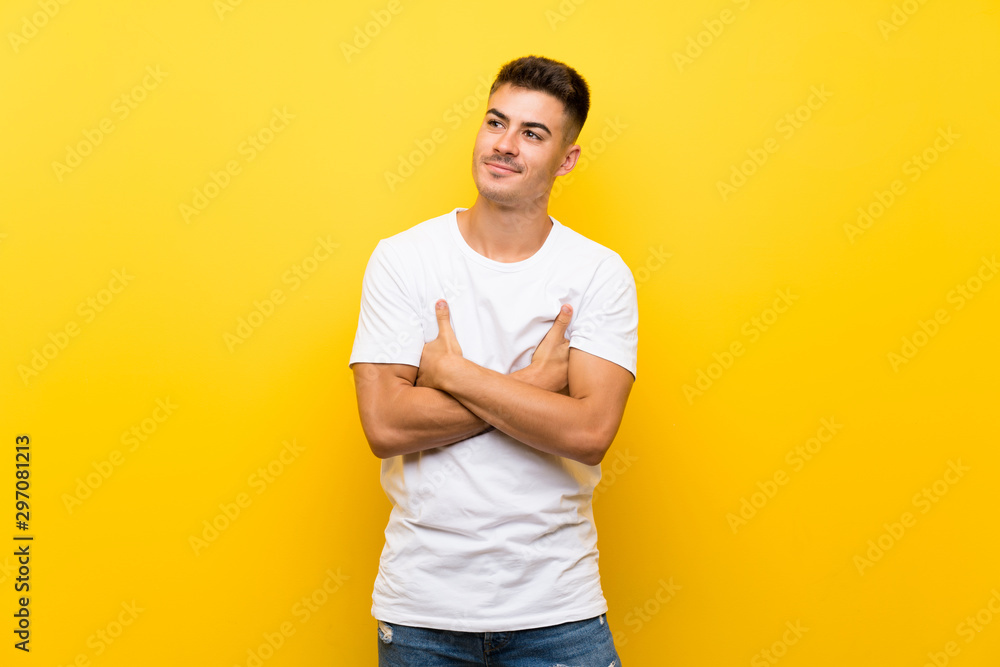 Young handsome man over isolated yellow background looking up while smiling Young handsome man over isolated yellow background looking up while smiling
