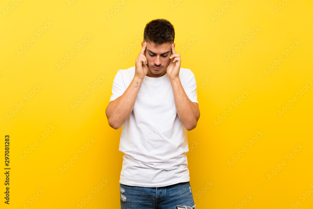 Young handsome man over isolated yellow background with headache Young handsome man over isolated yellow background with headache