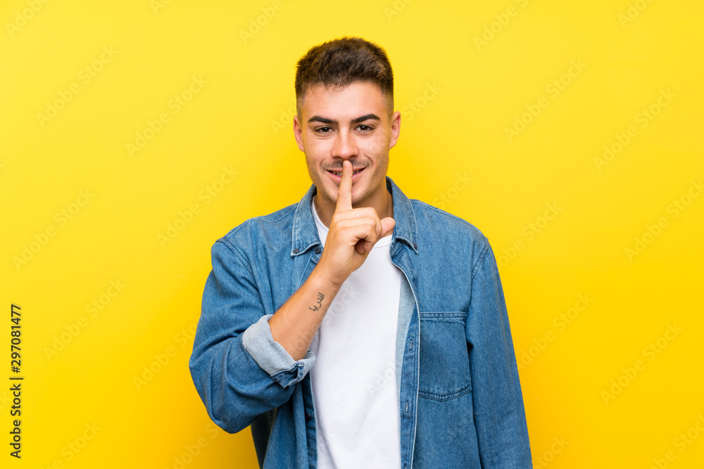 Young handsome man over isolated yellow background doing silence gesture Young handsome man over isolated yellow background doing silence gesture