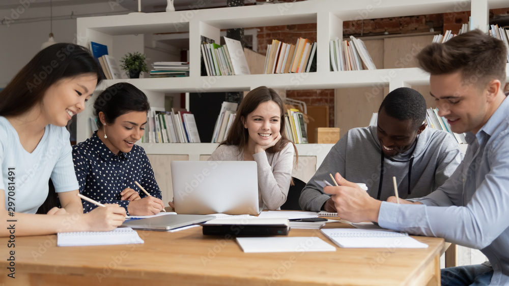 Multi-racial students study together seated at library desk Multi-racial students study together seated at library desk