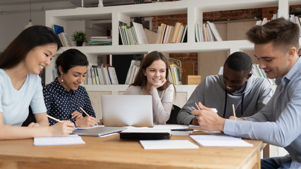 Multi-racial students study together seated at library desk