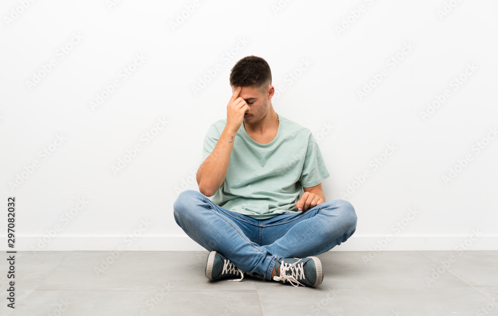 Young handsome man sitting on the floor laughing Young handsome man sitting on the floor laughing