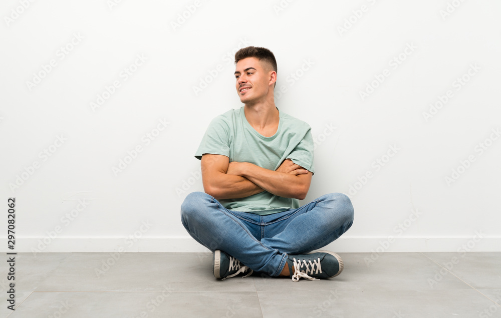 Young handsome man sitting on the floor looking to the side Young handsome man sitting on the floor looking to the side