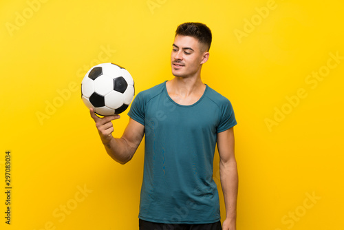 Handsome young football player man over isolated yellow background with happy expression