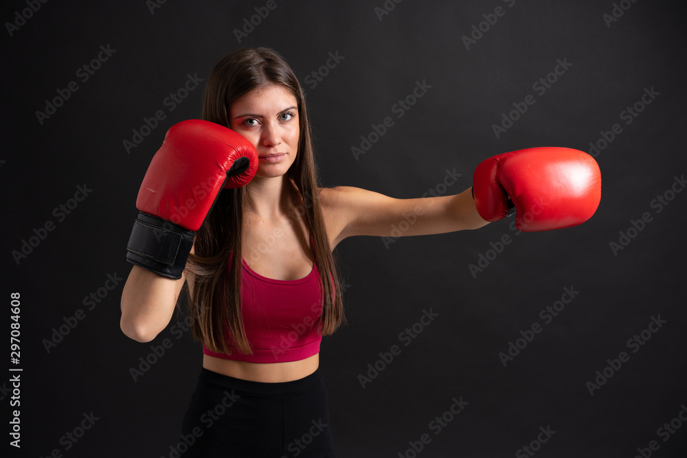 Young sport woman with boxing gloves over isolated black background Young sport woman with boxing gloves over isolated black background