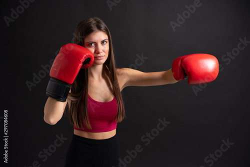 Young sport woman with boxing gloves over isolated black background