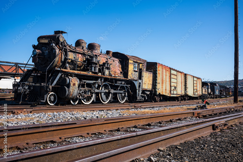 Naklejka premium Vintage train cars and locomotives, covered in rust and are in disrepair, rest on tracks in Scranton, PA, USA.