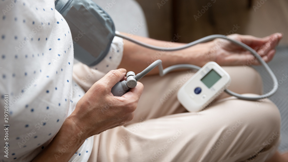 Old woman hypertension sufferer measure blood pressure hold electronic tonometer
