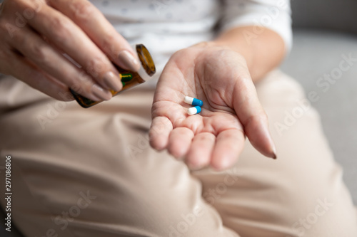 Senior woman holding pills capsules on hand  close up view