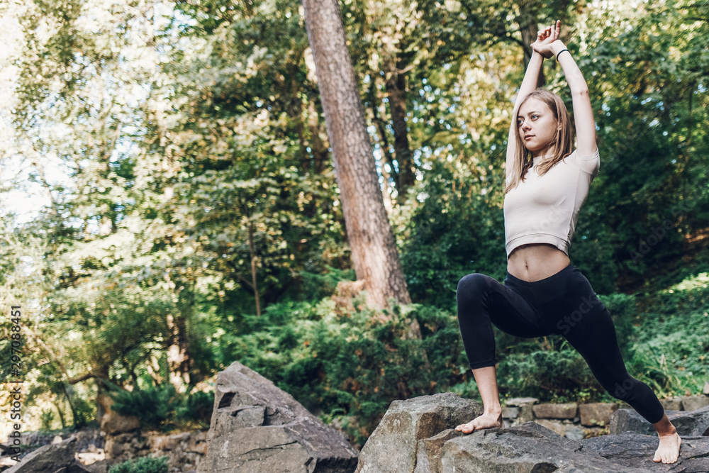 Young girl deepens yoga while doing exercises in the park on the rocks. Yoga exercicise outdoor Young girl deepens yoga while doing exercises in the park on the rocks. Yoga exercicise outdoor