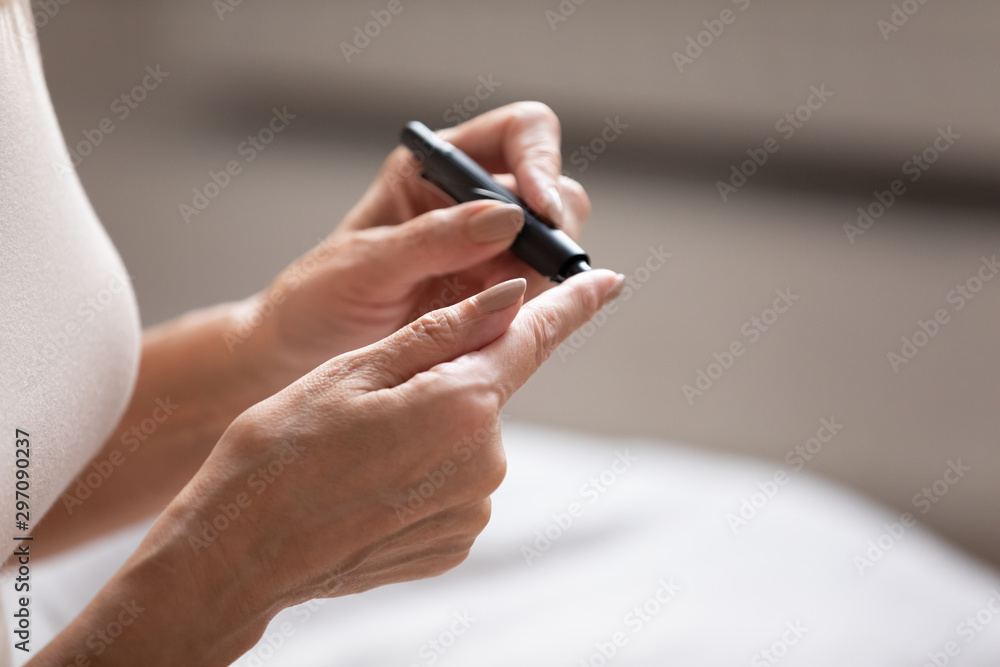 Older mature diabetic woman using blood glucose meter, close up Older mature diabetic woman using blood glucose meter, close up