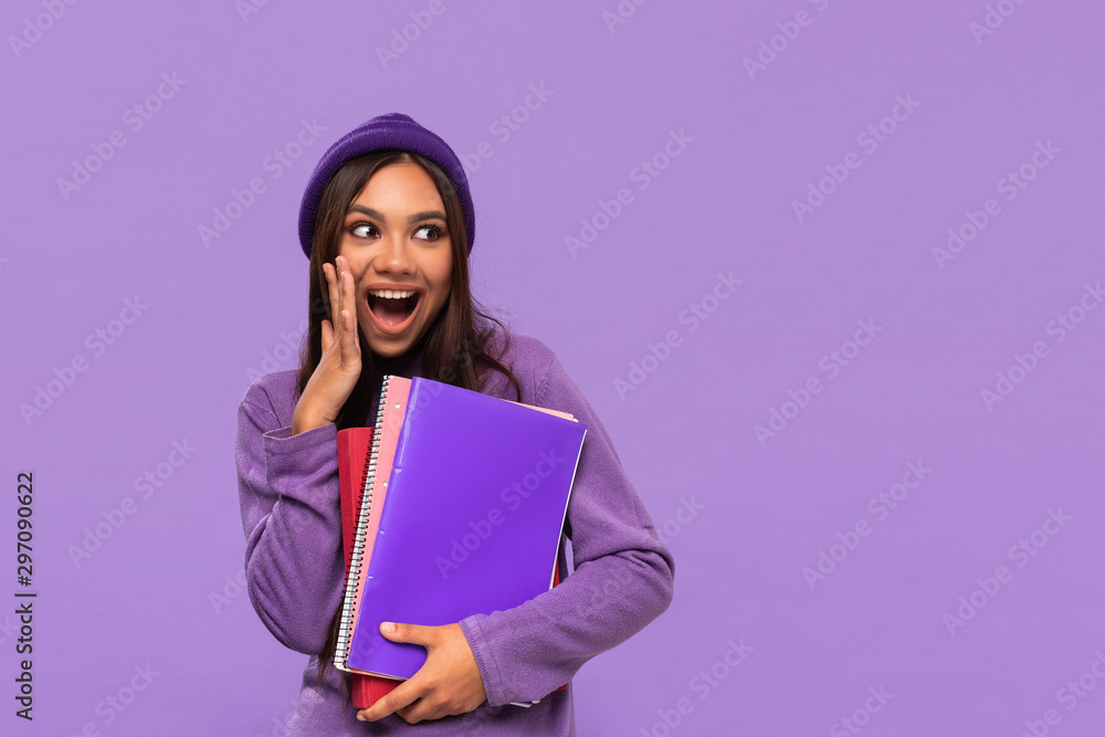 custom made wallpaper toronto digitalPretty african-american teenager in a hat and sweater holding folders and expressing emotion of surprise standing isolated over purple background.