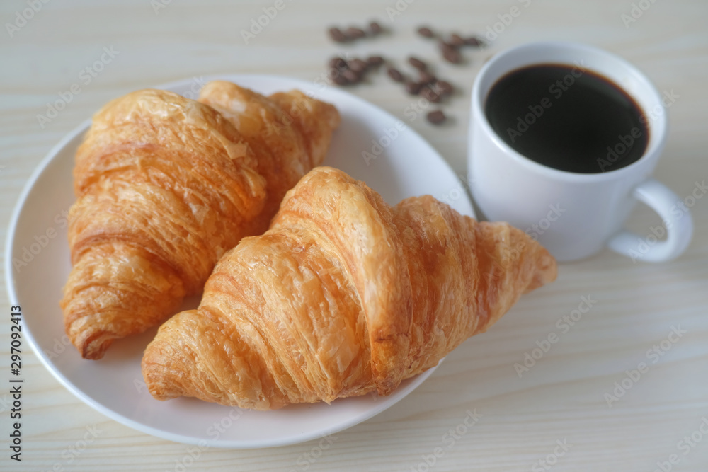 Delicious breakfast with fresh croissants and cup of espresso coffee on wood table.