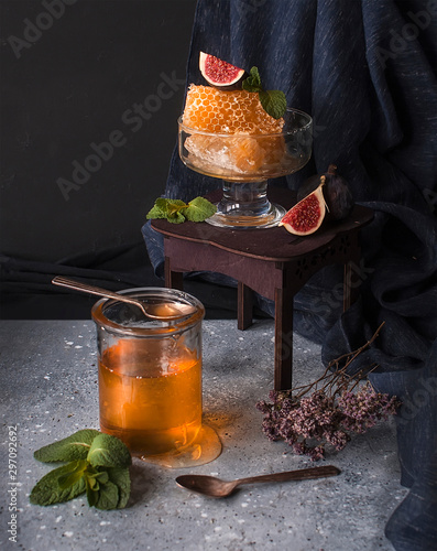 Honey in a jar and honey in a honeycomb on a dark background photo