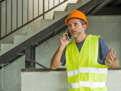 Konstfotografi upset construction worker or stressed contractor man in hardhat and vest talking