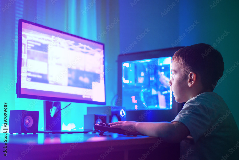 Boy play game on gaming computer or hacking a website concept. Dark scene with lots of RGB lighting. Boy play game on gaming computer or hacking a website concept. Dark scene with lots of RGB lighting.