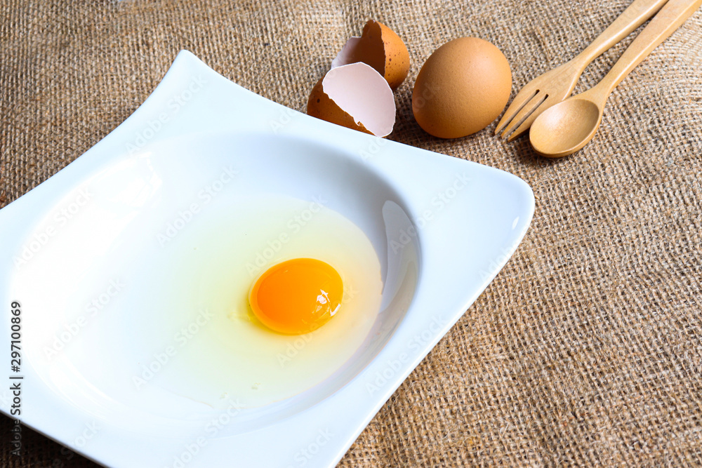 Raw Organic round (White eggs and yolk )of chicken decorative food concept With eggshell and spoon and fork isolated In a white ceramic container background texture close-up Raw Organic round (White eggs and yolk )of chicken decorative food concept With eggshell and spoon and fork isolated In a white ceramic container background texture close-up