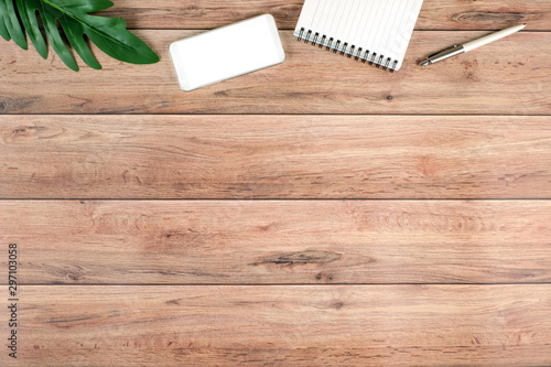 Work space vintage wooden office desk table with blank notepad and blank screen phone, Top view with copy space