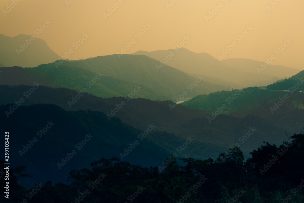 Summer mountain forest layers landscape in sunset.