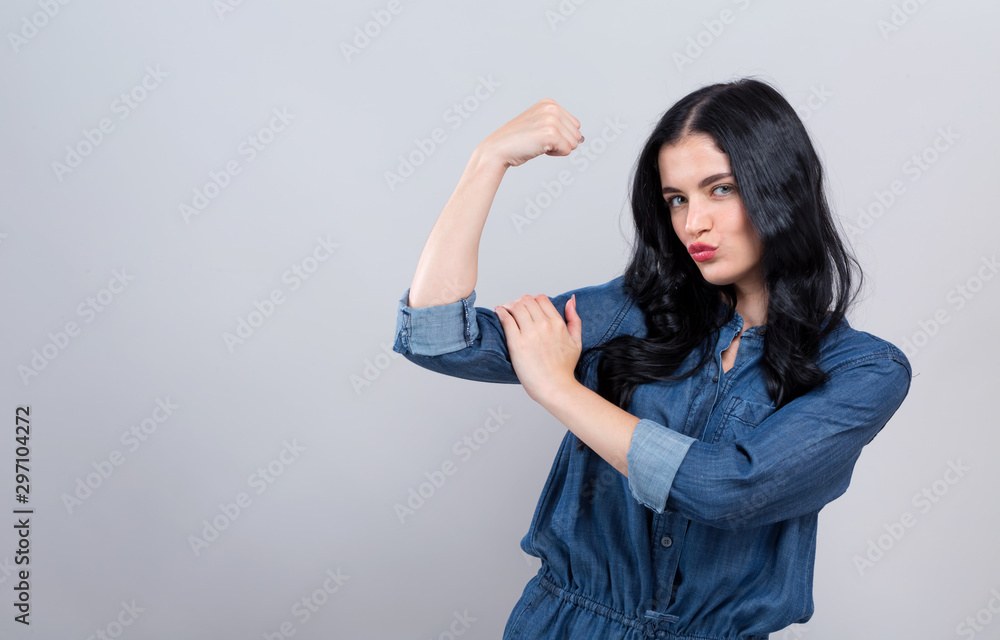 Powerful young woman in a success pose on a gray background Powerful young woman in a success pose on a gray background