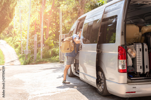 Passenger boarding on travel van with carry bag and bottle water.