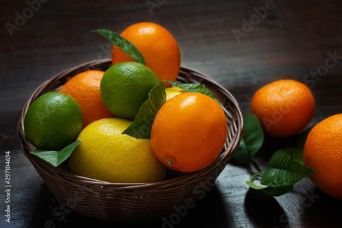 Juicy ripe slices of orange, lemon, grapefruit and lime on a dark background. Sliced citrus in a basket on a brown wooden table. Fruit mix, top view close-up.