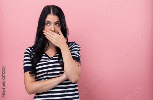 Fotografie Young woman covering her mouth on a pink background