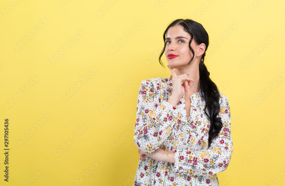 Young woman in a thoughtful pose on a yellow background Young woman in a thoughtful pose on a yellow background