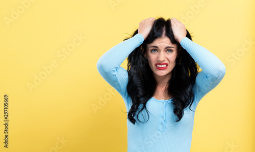 Young woman feeling stressed on a yellow background