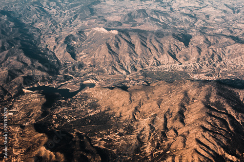 Aerial view from the plane on the panorama of the Alp mountains and hills ridge. Mountain peak of rocks covered by clouds and fog. View from above on mountain landscape.
