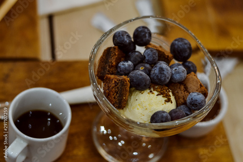 chocolate cookies with blueberries and ice cream in a glass vase and a cup of coffee