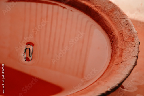 paper clip in red water in a clay plate
