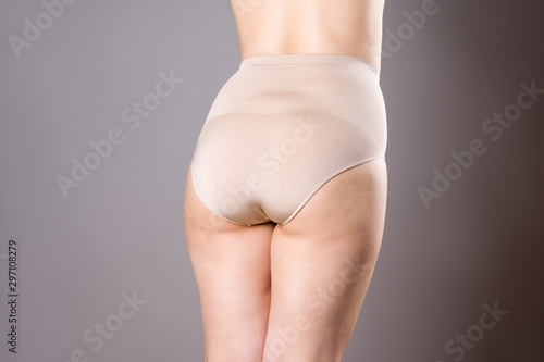 Woman in corrective panties, overweight female body in shapewear on gray background