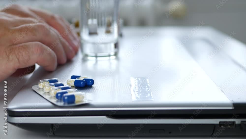 Suffering Man Take Pills from the Laptop with Shacking Hands Suffering Man Take Pills from the Laptop with Shacking Hands