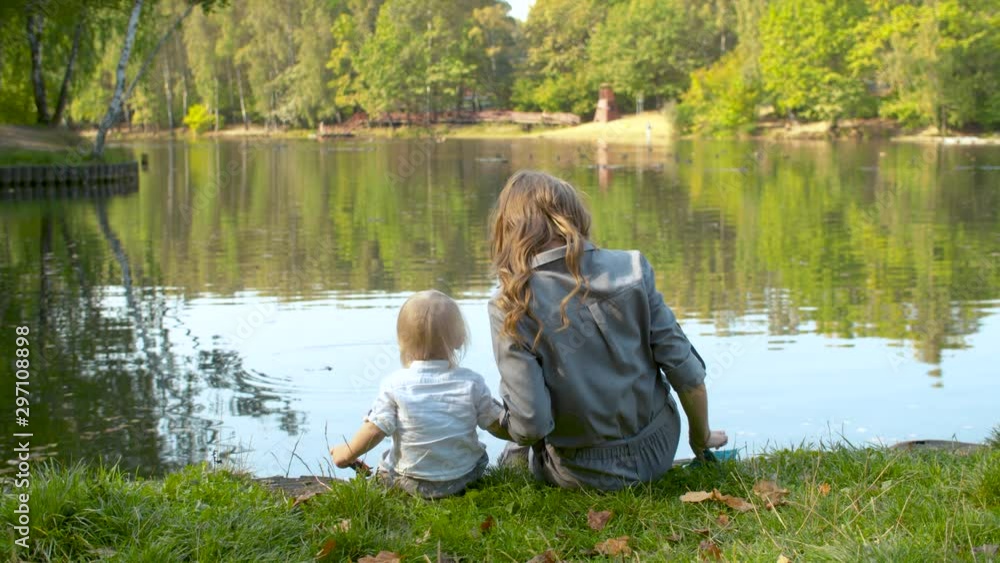 A young mother and her toddler are feeding the ducks on a lake A young mother and her toddler are feeding the ducks on a lake