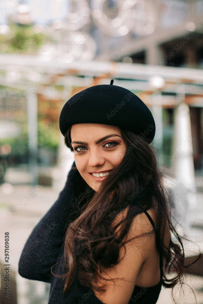 smiling curly brunette woman in retro hat enjoying life in the city. smiling curly brunette woman in retro hat enjoying life in the city.