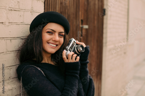 happy smiling woman in hat holding retro camera and taking picture