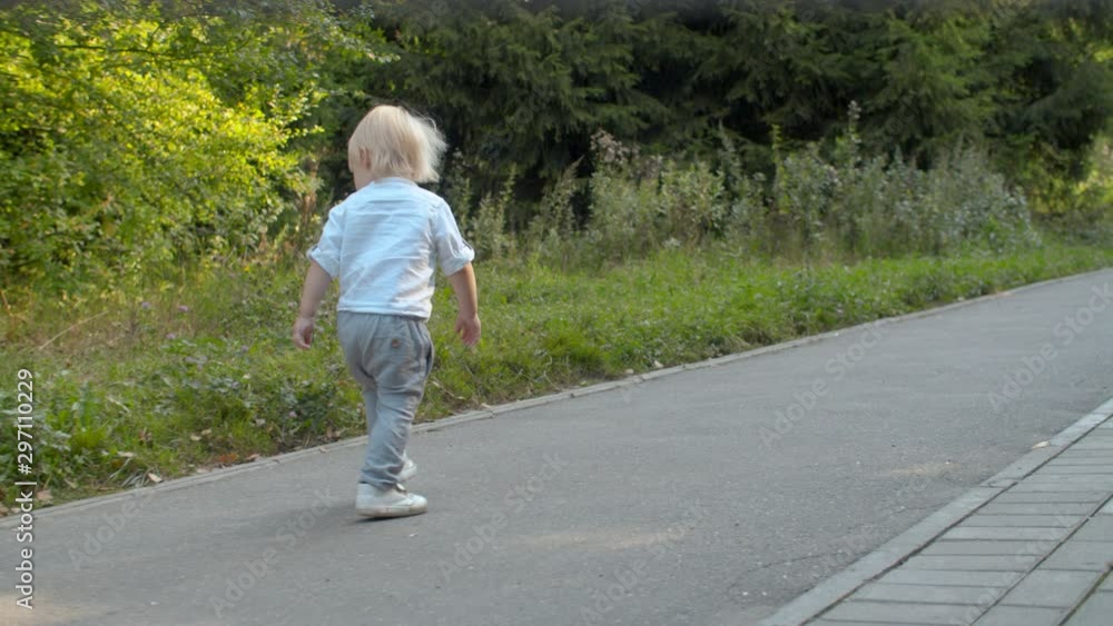 Little boy walking along the road in the park Little boy walking along the road in the park