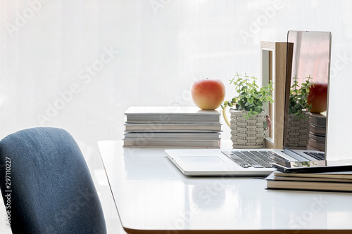 Office desk wih laptop blank screen and stack of books. Over light backlground. photo