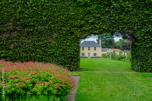 Building view through the opening in a long bush fence at the Royal Botanic Garden in Edinburgh, Scotland