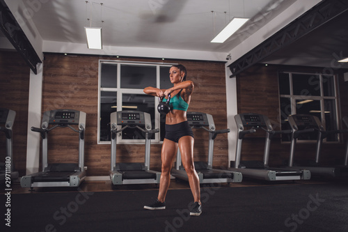 Fit girl with kettle-bell exercise in gym