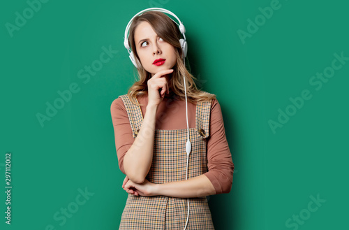 woman in vintage dress with headphones on green background