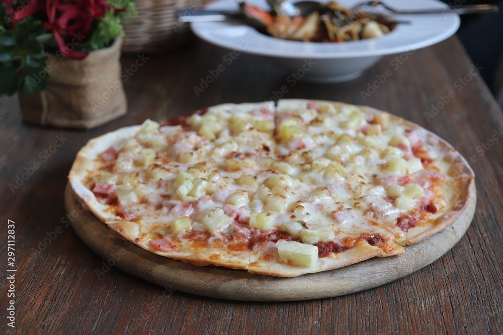 Hawaiian pizza in wooden tray on the table Hawaiian pizza in wooden tray on the table