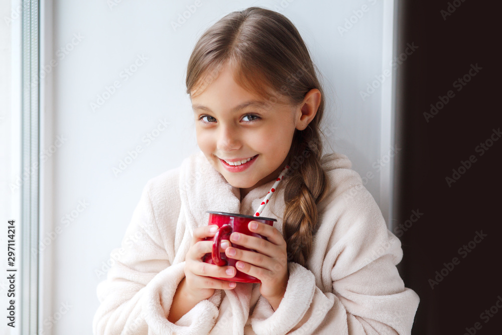 Cute girl sitting on the window, drinking cocoa and reading a book in room at home. Cute girl sitting on the window, drinking cocoa and reading a book in room at home.