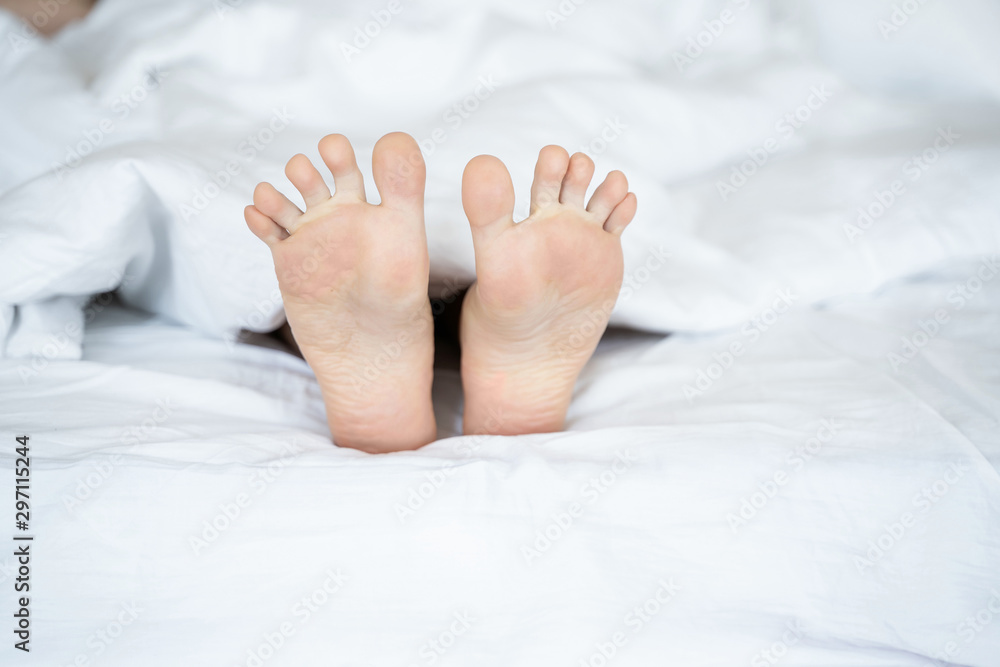 Caucasian young woman feet lying in bed Caucasian young woman feet lying in bed