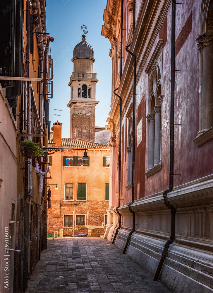 Traditional street, church and colorful Venetian houses in Venice, Italy.